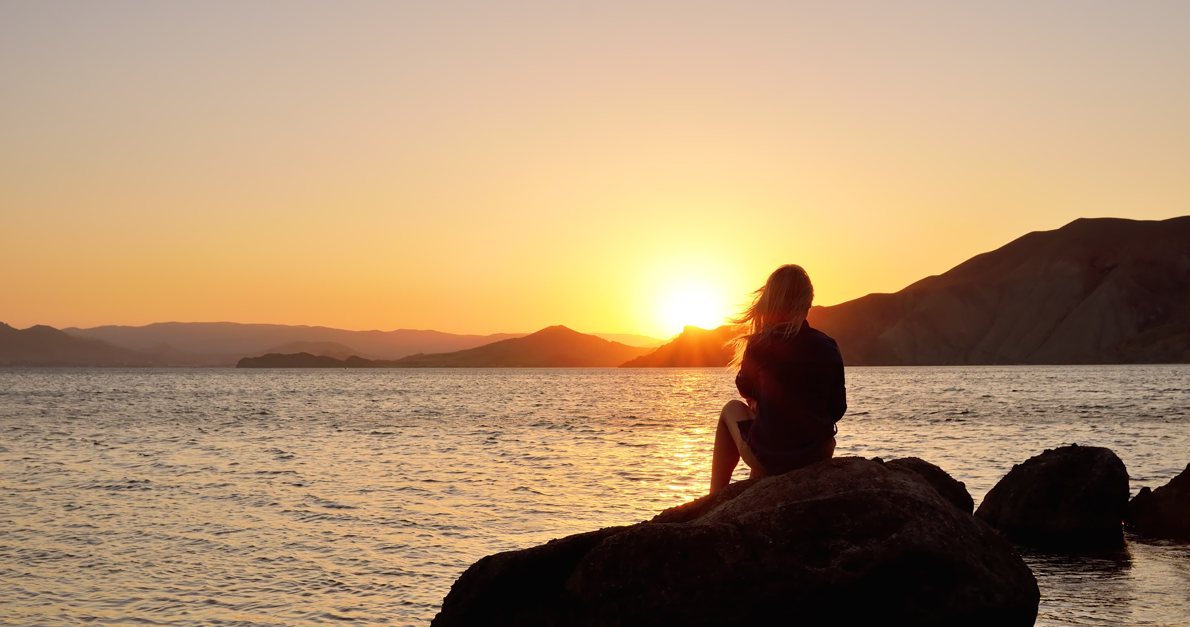 Woman reflecting by the ocean at sunset, symbolizing low self-esteem in relationship, emotional loneliness, and self-worth healing