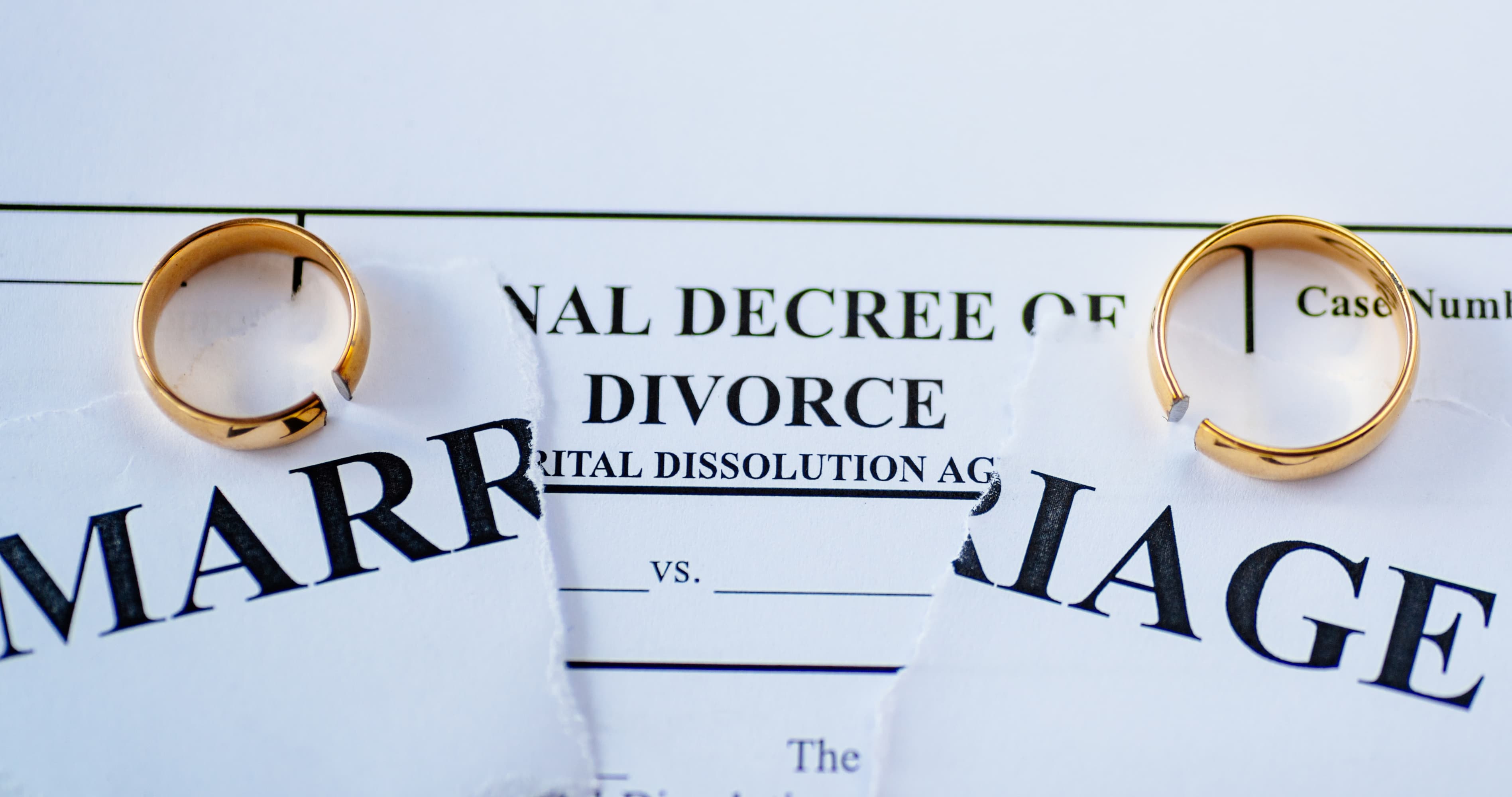 Broken wedding rings on a torn divorce paper representing how to avoid divorce and save a struggling marriage.