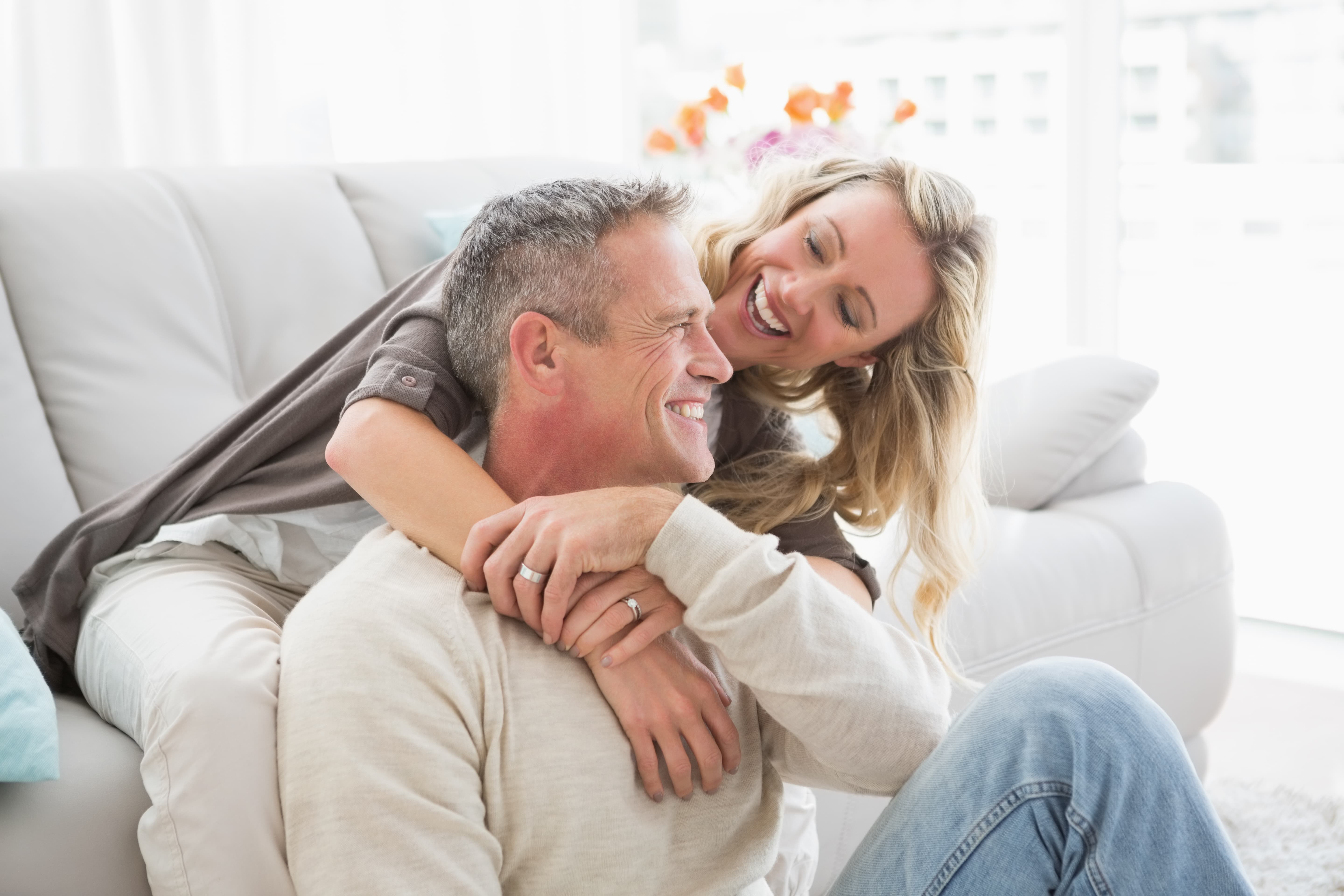Happy couple laughing and embracing at home, representing how to feel secure in a relationship through trust, comfort, and emotional connection.