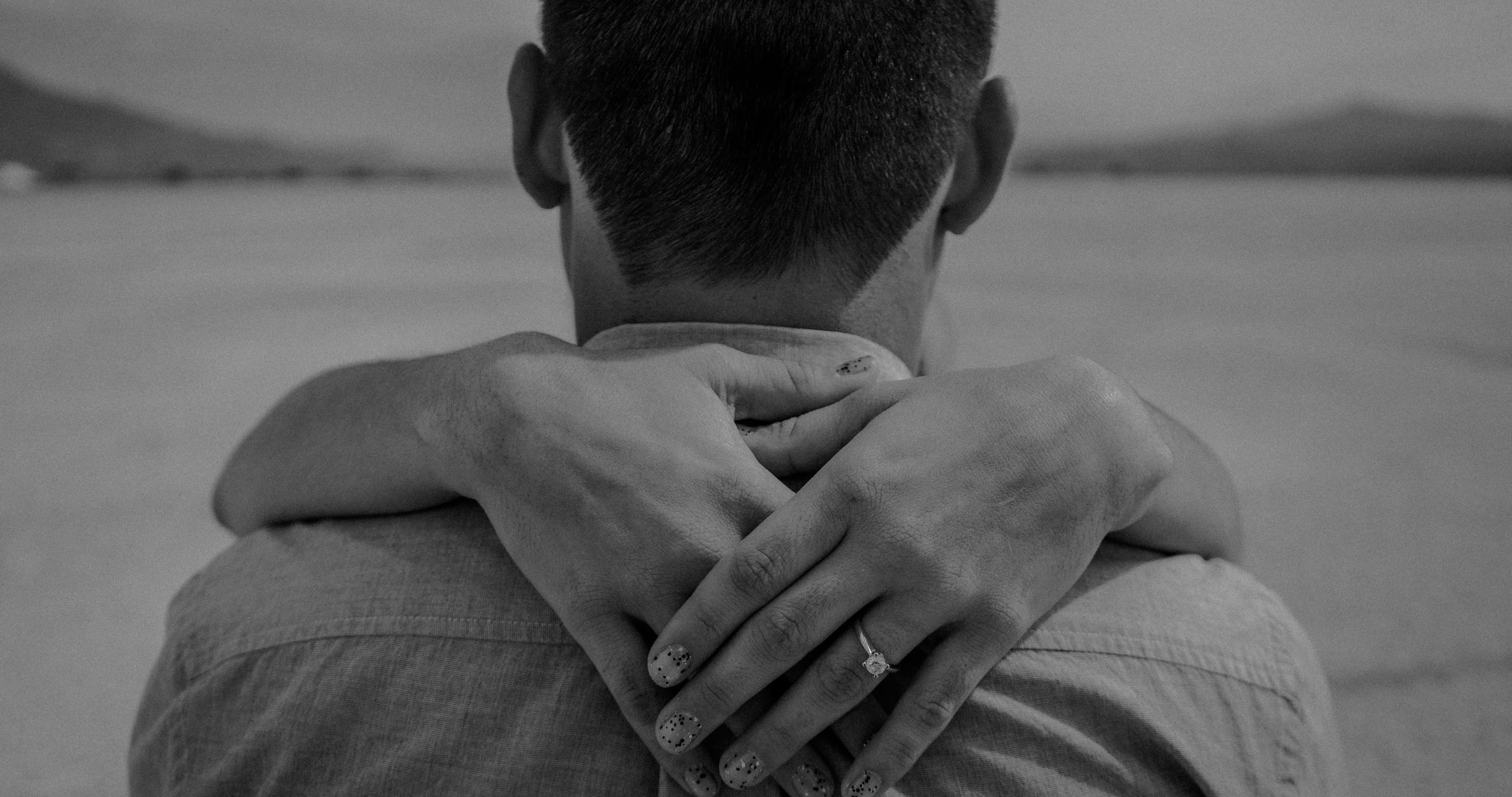 Woman hugging her boyfriend from behind in a black and white romantic relationship photo, showing love, intimacy, emotional connection, and how to make your boyfriend feel closer to you.