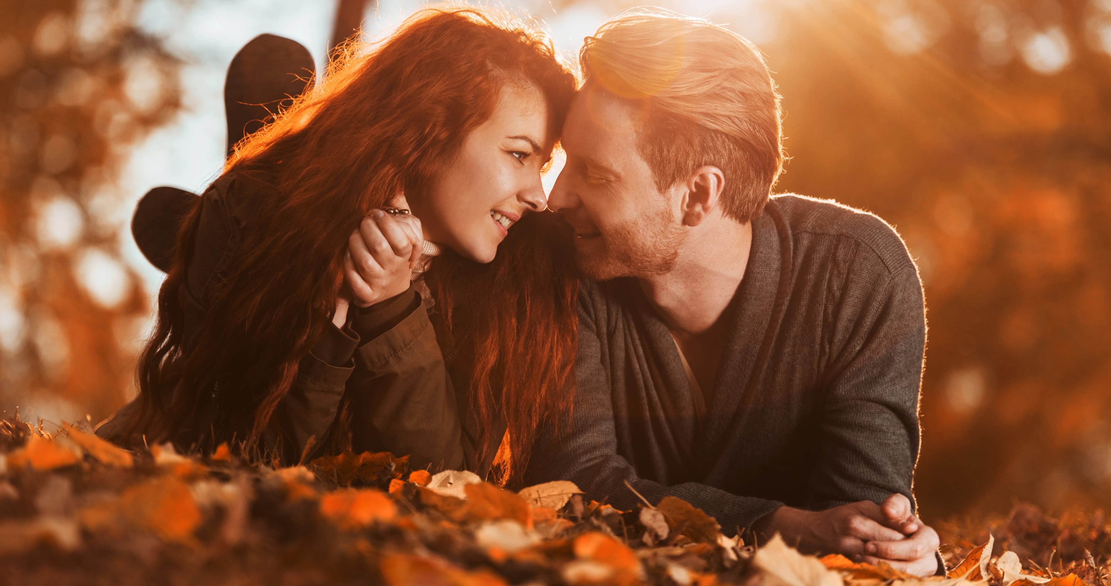 Couple lying together in autumn leaves, showing love, emotional connection, and how to rebuild trust in a relationship.