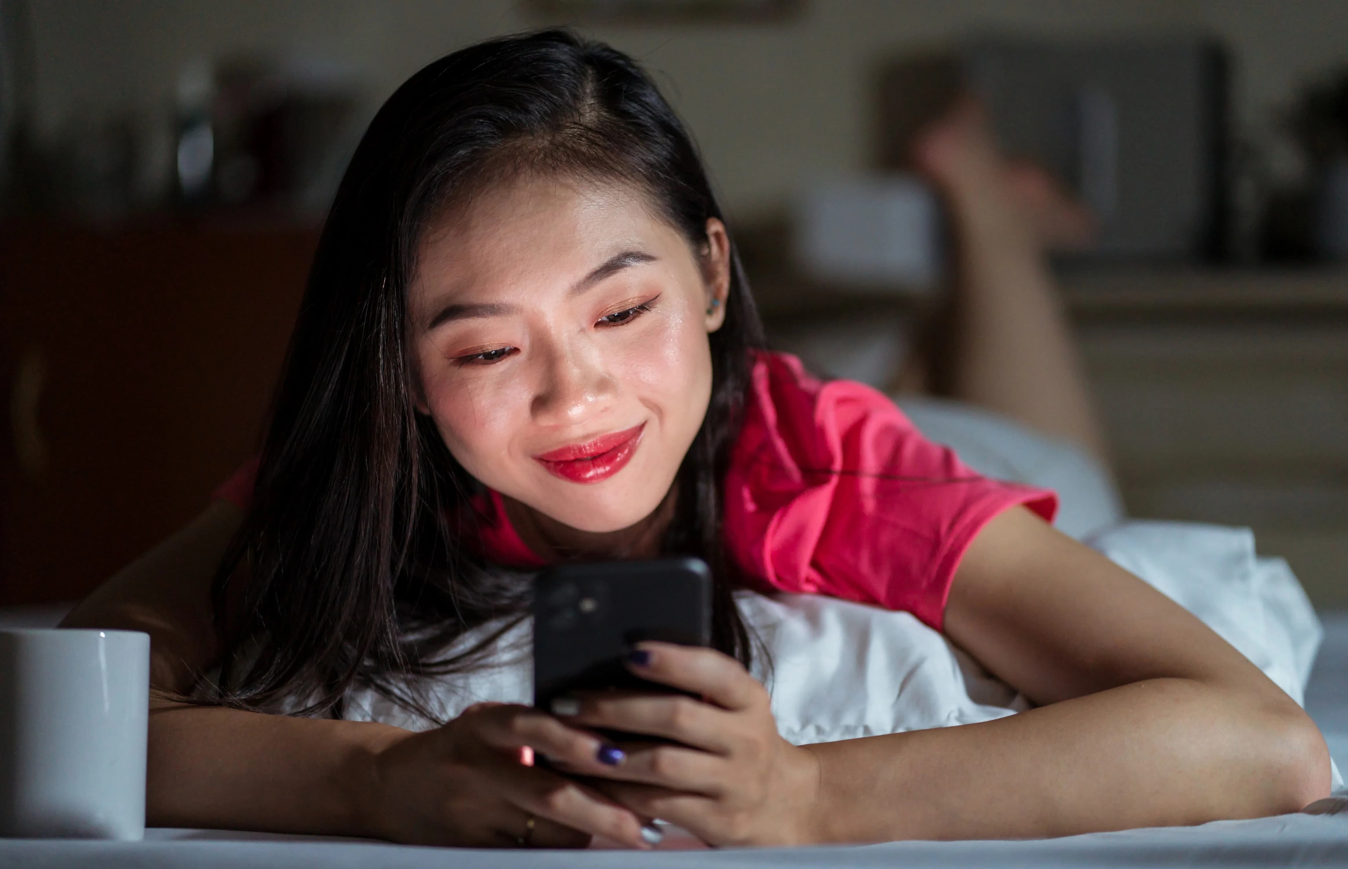 Young woman texting on her phone in bed, symbolizing how modern dating got so guarded and emotionally cautious