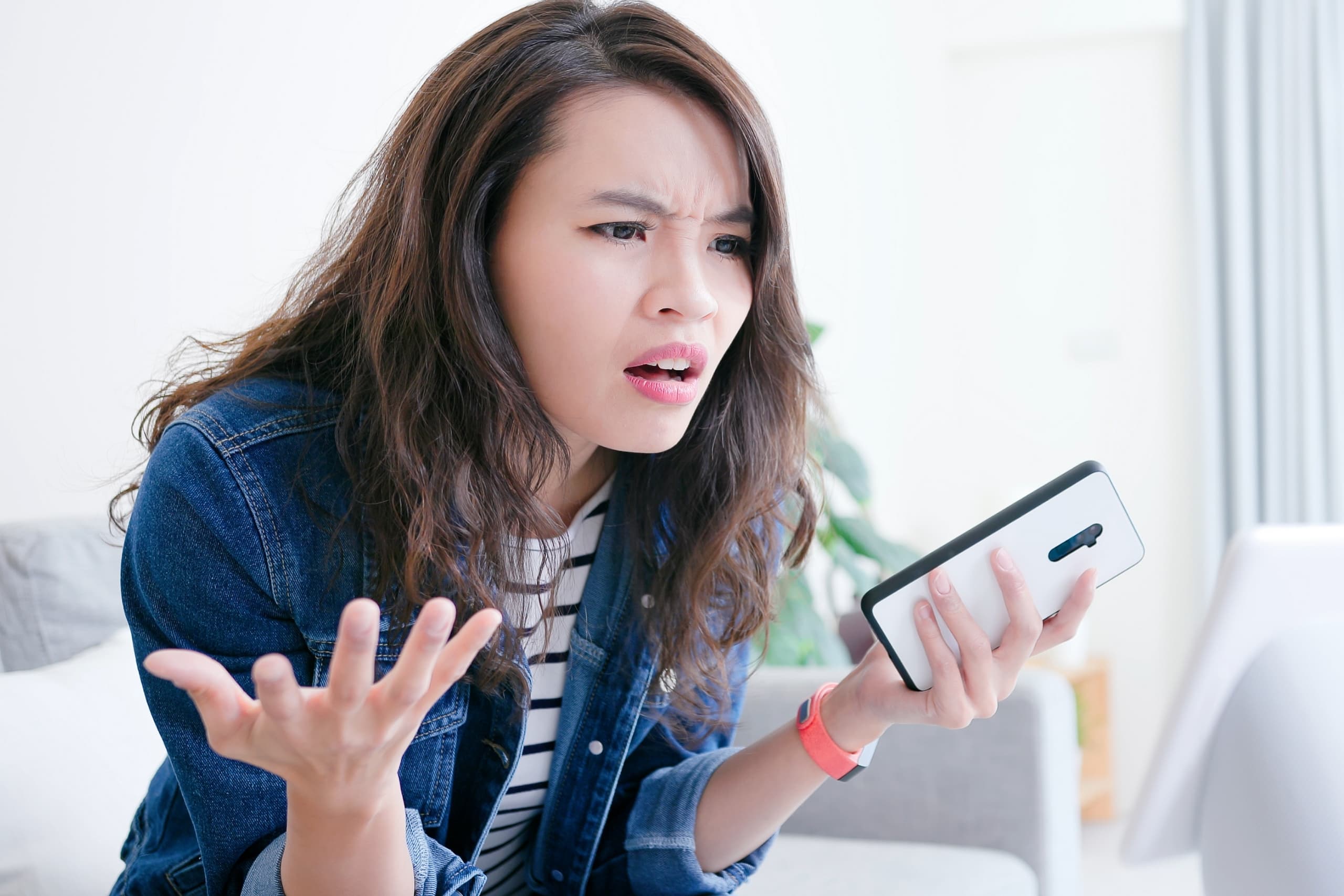 Confused young woman looking at a text on her phone, frustrated by her ex's mixed signals