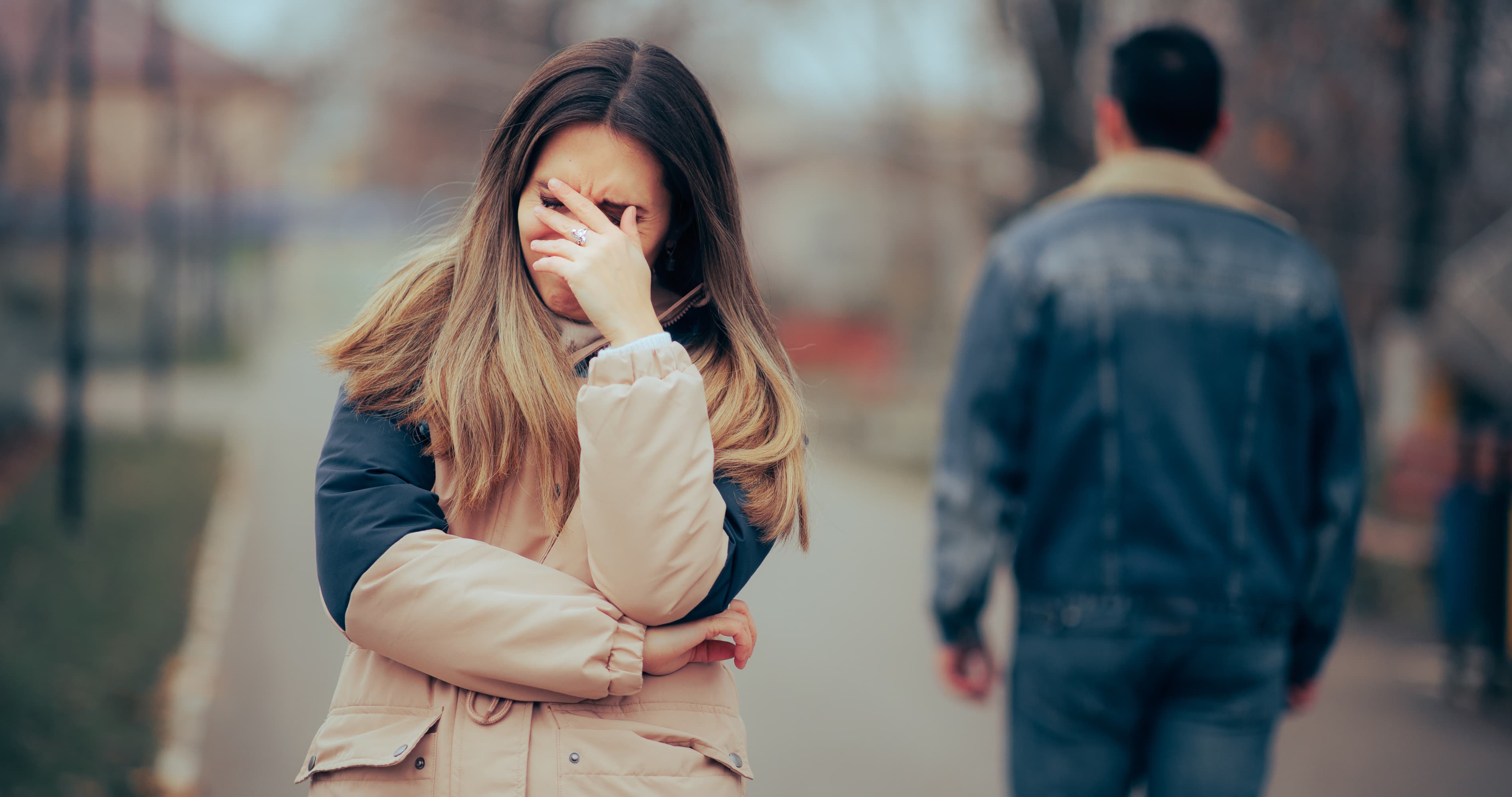Woman crying after a breakup as a man walks away, illustrating what to do after a breakup and healing from heartbreak.